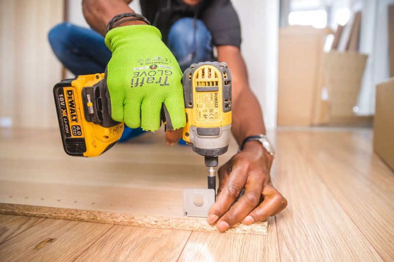 Hands using a yellow cordless drill on a wood project